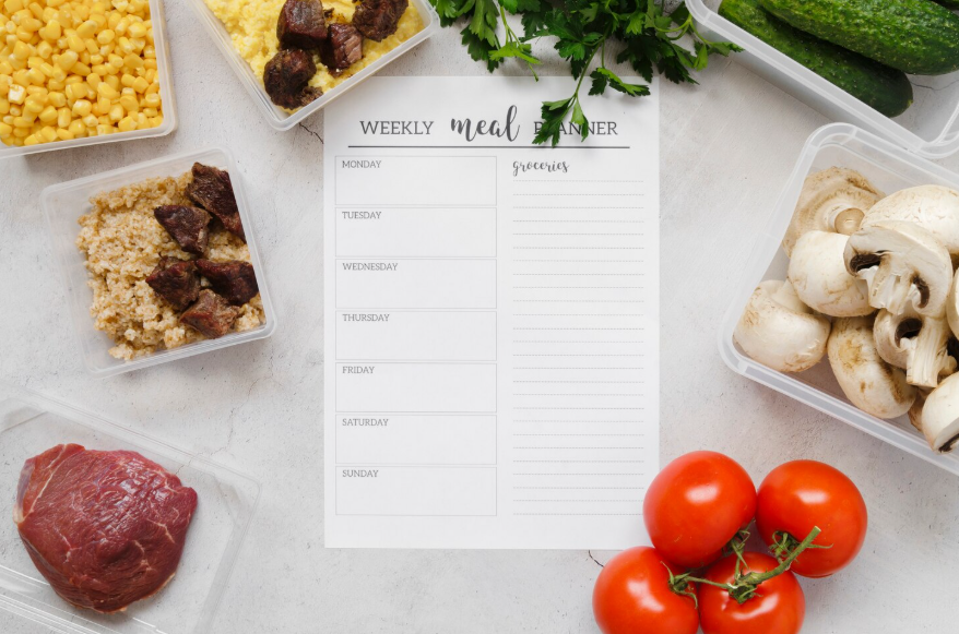 weekly planner and groceries for a realistic weekly meal plan on a kitchen counter