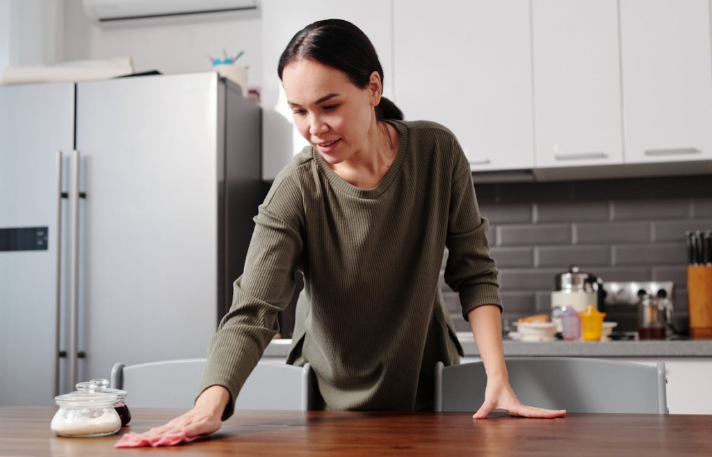 person wiping down a kitchen table during a Sunday kitchen reset routine at home